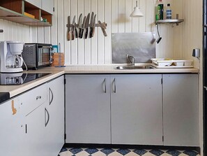 A kitchen with a coffee maker, toaster, microwave, sink, and hanging knives. - 5 Person Holiday Home in Karrebaeksminde (Karrebæksminde)