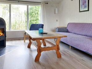A cozy room with a wooden table, a sofa, and a fireplace. - 5 Person Holiday Home in Karrebaeksminde (Karrebæksminde)