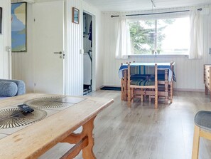 A room with a wooden table, a dining table with chairs, a sofa, and a window with curtains. - 5 Person Holiday Home in Karrebaeksminde (Karrebæksminde)