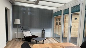 Une pièce moderne dotée d’une grande fenêtre, d’un fauteuil confortable, d’une table et d’une lampe.