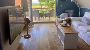 Ett mysigt vardagsrum med en vit soffa, ett litet soffbord och utsikt över en uteplats genom en glasdörr.