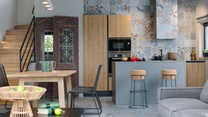 Une cuisine moderne équipée d’un four à micro-ondes, d’une cuisinière et de tabourets de bar. On y trouve également un coin repas avec une table et des chaises, ainsi qu’un escalier avec des marches en bois.