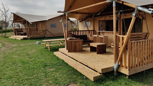 A wooden cabin with a deck, a picnic table, and a sheltered seating area. - Flevoland Glamping Escape (Bant)