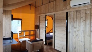 A wooden cabin interior with a kitchen area, a bed, and a bathroom. - Flevoland Glamping Escape (Bant)