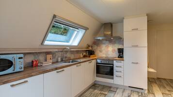 A modern kitchen with a skylight, white cabinets, a microwave, a coffee maker, and a built-in oven.