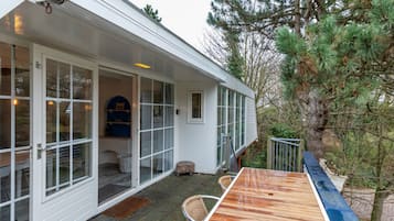 A modern house with large glass doors leading to a covered patio area.