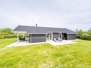 A modern house with a covered patio, a garage, and a lawn.