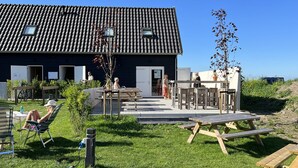 En bygning med tegltag, udendørs siddepladser og en græsplæne med et picnicbord.