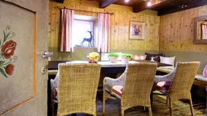 A rustic wooden room with wicker chairs, a table with a vase of flowers, and a window with a deer silhouette. - Farmhouse in Hollersbach Near Kitzski (Hollersbach im Pinzgau)