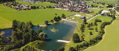 An aerial view of a small town with a central church, green fields, and a lake.