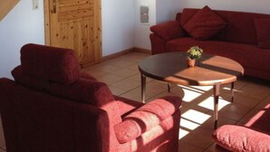 Ein Wohnzimmer mit einer Holztreppe, roten Möbeln und einer Holztür mit einer Lampe.