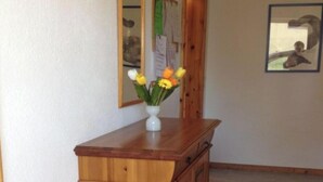 Ein Flur mit einem Holzkabinett, einem Spiegel und einem Teppich mit Muster.