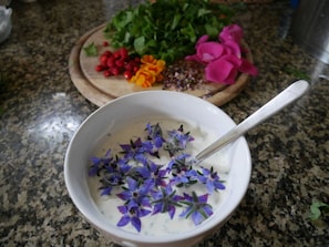 A bowl of yogurt with purple flowers on a granite countertop. - Holiday Apartment Wellness & Relaxation (Wunsiedel)