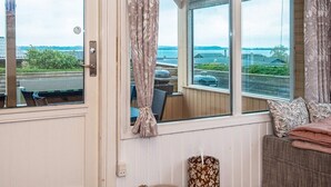 Una habitación con un ventanal grande, una puerta y un área de descanso con sofá y cojines.