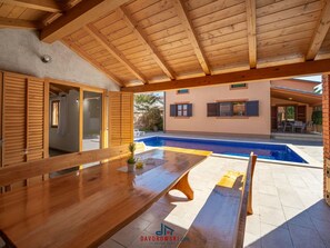 Une terrasse en bois avec une piscine, une table et un banc.