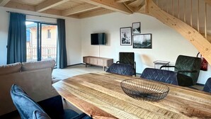 Uma sala de estar ampla com uma mesa de jantar de madeira, um sofá e uma escada.