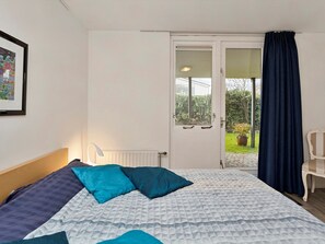 A bedroom with a bed, a window, a door, and a chair. - Lovely Family Villa With Garden in Kamperland (Kamperland)