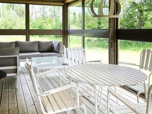 Un espace extérieur aménagé, abrité et doté d’une table et de chaises, d’un canapé, et offrant une vue sur la végétation environnante.