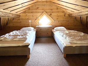 A small, cozy attic bedroom with two beds, a nightstand, and a window with a view. - 4 Star Holiday Home in Tranas (Tranas)