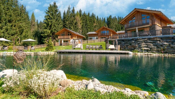 A lakeside lodge with wooden cabins, a clear lake, and a stone wall. - Chalet in Wolting in a Delightful Area (Tamsweg)