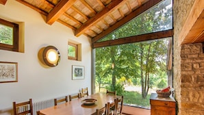 A dining area with a wooden table and chairs, large windows, and framed artwork on the walls. - Villa in Borgo Pace With Private Pool (Borgo Pace)