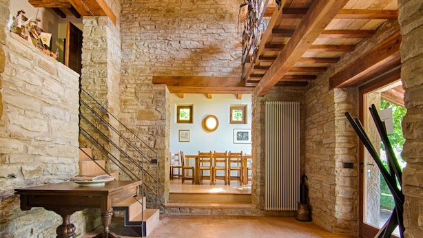 A rustic interior with stone walls, a wooden staircase, a dining area with wooden chairs, and a radiator. - Villa in Borgo Pace With Private Pool (Borgo Pace)