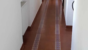 Un pasillo con baldosas marrones estampadas y paredes blancas.