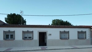 Un edificio de dos plantas con techo de tejas, una puerta central y ventanas con rejas.