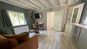 A spacious living area with a sofa, a dining table, and a kitchen area. - Holiday Home in Schoonloo With Balcony/terrace (Schoonloo)