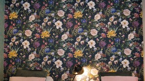 A bedroom with two beds, a nightstand with a lamp, and a floral wallpaper. - Holiday Home in Schoonloo With Balcony/terrace (Schoonloo)