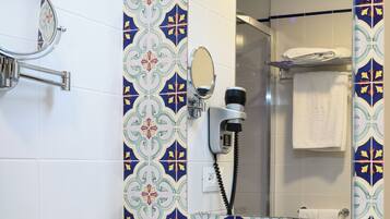 Un baño con lavamanos blanco, espejo, secador de pelo y toallero.