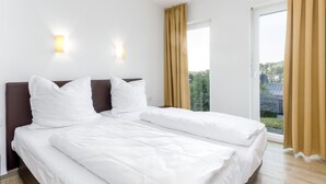 A hotel room with a double bed, two wall-mounted lights, a window with curtains, and a view of greenery outside. - Kurzurlaub im Waxweiler-tal (Waxweiler)