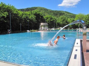 Ein Pool mit Wasserspiel, umgeben von einem bewaldeten Hang.