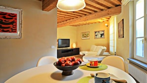 A dining area with a table set for two, a bowl of fruit, and a cup on the table. - Apartment in Lucca Near Amphitheater Square (Lucca)