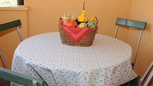 A round table with a white tablecloth, a wicker basket with fruits and vegetables, and two green chairs. - Moritzing am Prantenberg Gut (Bolzano)