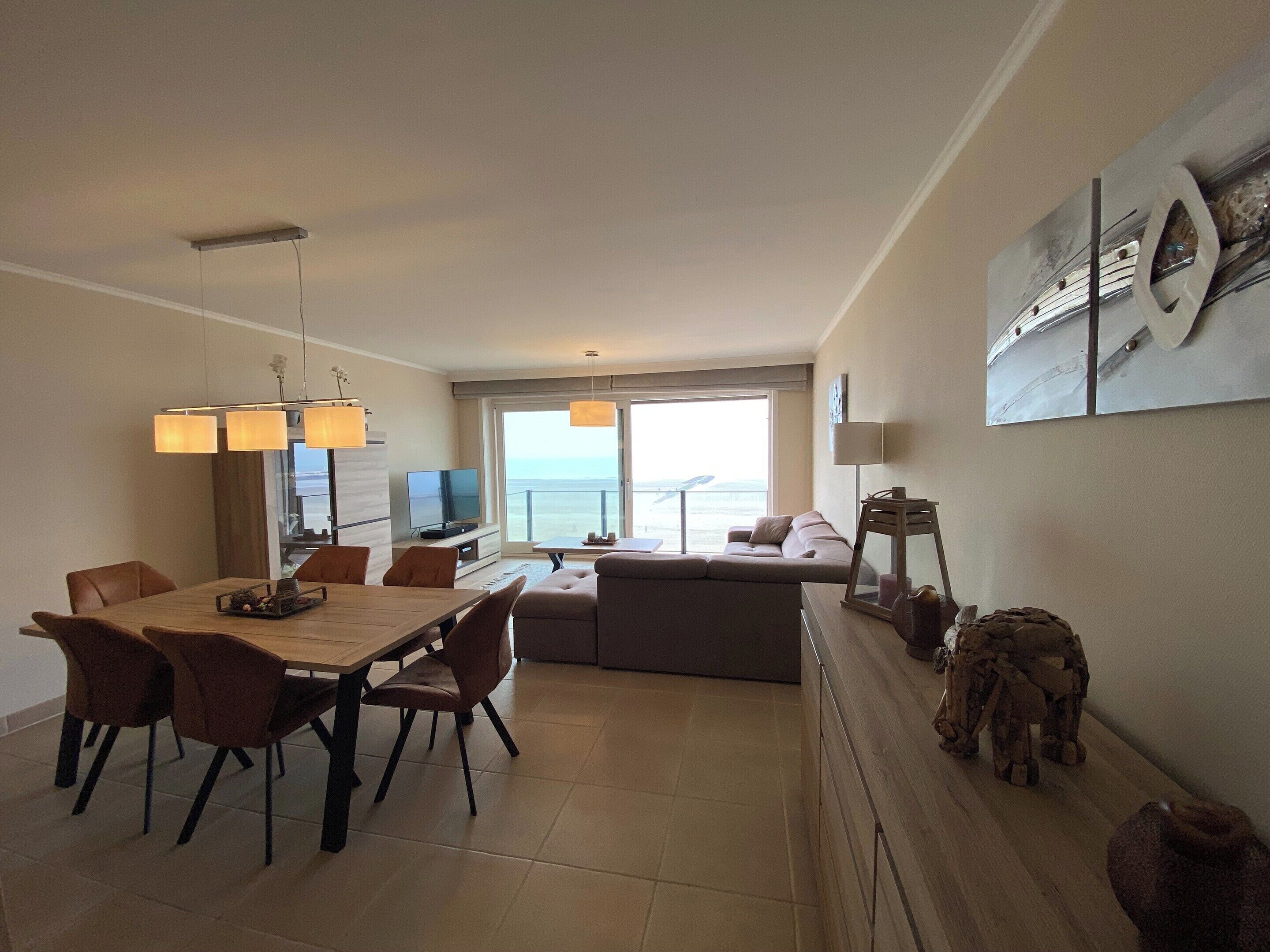 Una sala moderna con comedor, un sofá y un televisor.