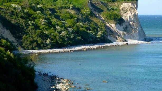A coastal landscape with a lighthouse, rocky shoreline, and lush greenery. - Just Before the Cape, Holiday Home B (Putgarten)
