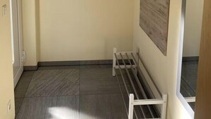 A narrow hallway with a bench, a wooden shelf with items, and a door. - Just Before the Cape, Holiday Home B (Putgarten)