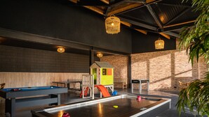 A recreational area with pool tables, a foosball table, and a children's play area. - Beautiful Holiday Home With hot tub (Losser)