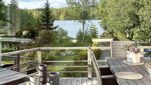 A wooden deck with a view of a lake, outdoor furniture, and potted plants. - 4 Star Holiday Home in Vintrosa (Vintrosa)