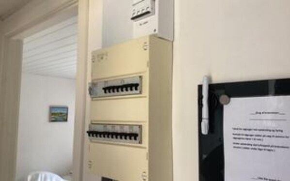 A control panel with multiple switches and a document attached to a wall.