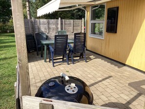 An outdoor patio with a table and chairs, a grill, and a wooden fence. - 4 Star Holiday Home in Hals (Hals)