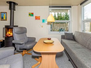A modern living room with a wood-burning stove, grey upholstered furniture, and artwork on the walls. - 4 Star Holiday Home in Hals (Hals)