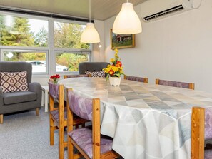 Un coin repas avec une grande table, des chaises et un vase de fleurs.