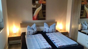 Ein Doppelbett mit gestreifter Bettdecke, zwei Nachttische mit Lampen.