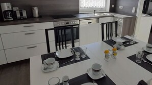 Een moderne keuken met een eethoek voor vier personen. Uitsluitend voorzien van een fornuis, oven, vaatwasser en een raam met gordijnen.