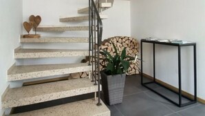 Una escalera de caracol con revestimiento de concreto, barandilla de metal negro y un gran cuadro de un paisaje montañoso en la parte superior.