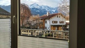 Habitación con vistas a una cordillera y un edificio blanco con contraventanas marrones.