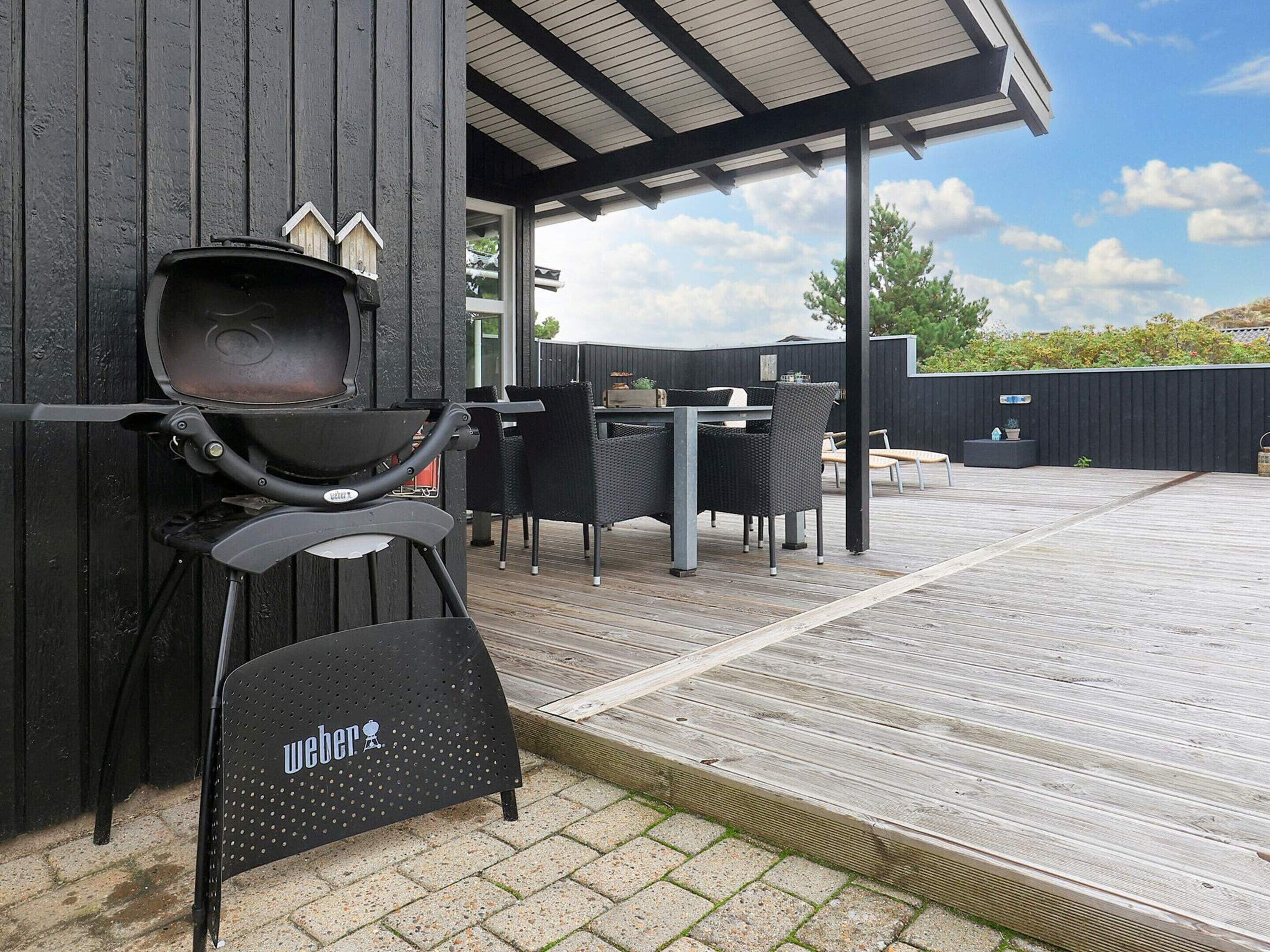 En grill, udendørs møbler og en træterrasse.