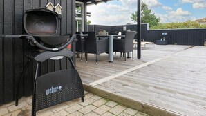 A barbecue grill, outdoor seating, and a wooden deck. - 4 Star Holiday Home in Henne (Henne)